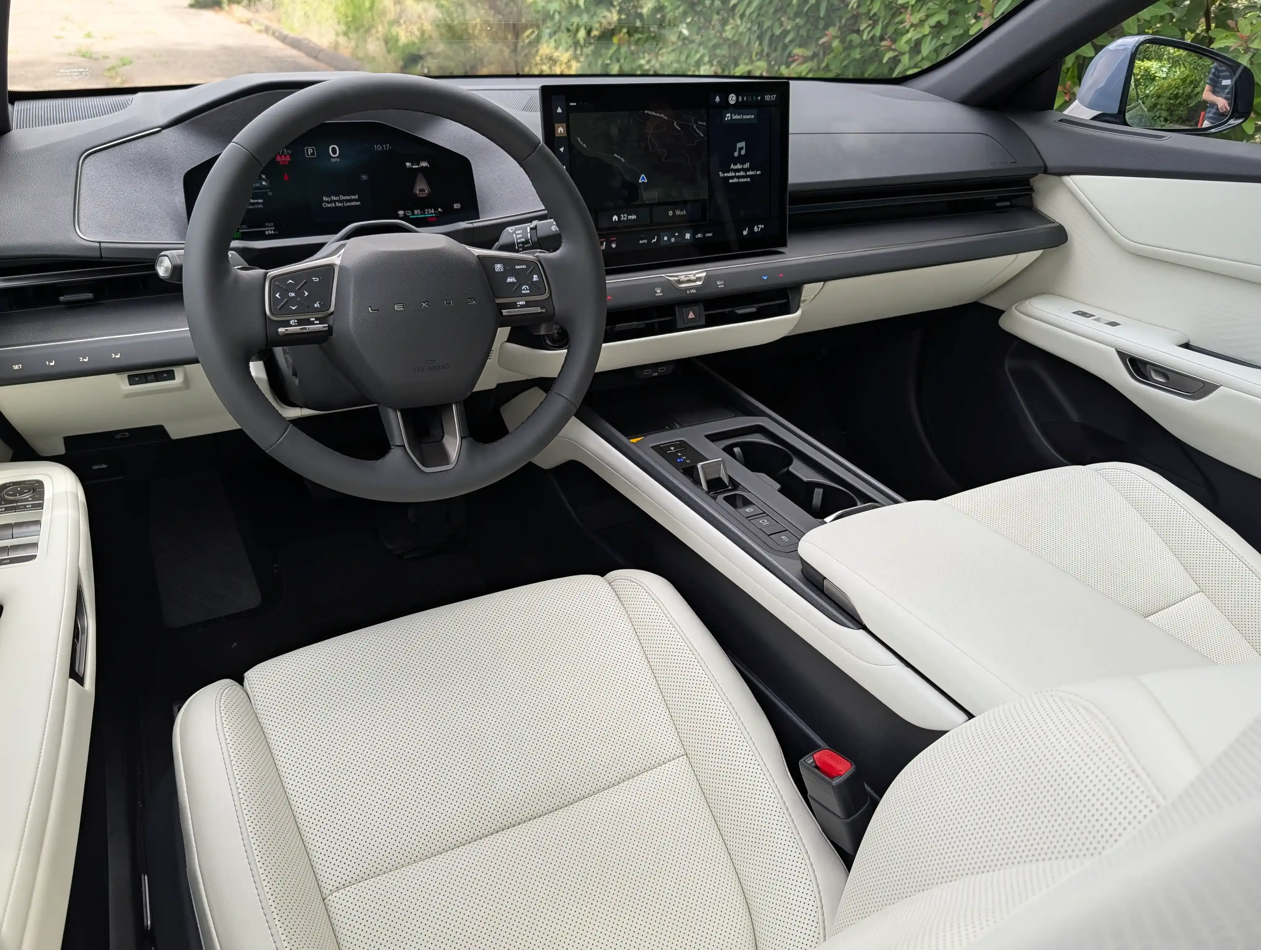 Front cabin view with a digital gauge cluster, large center touchscreen, and light upholstery.