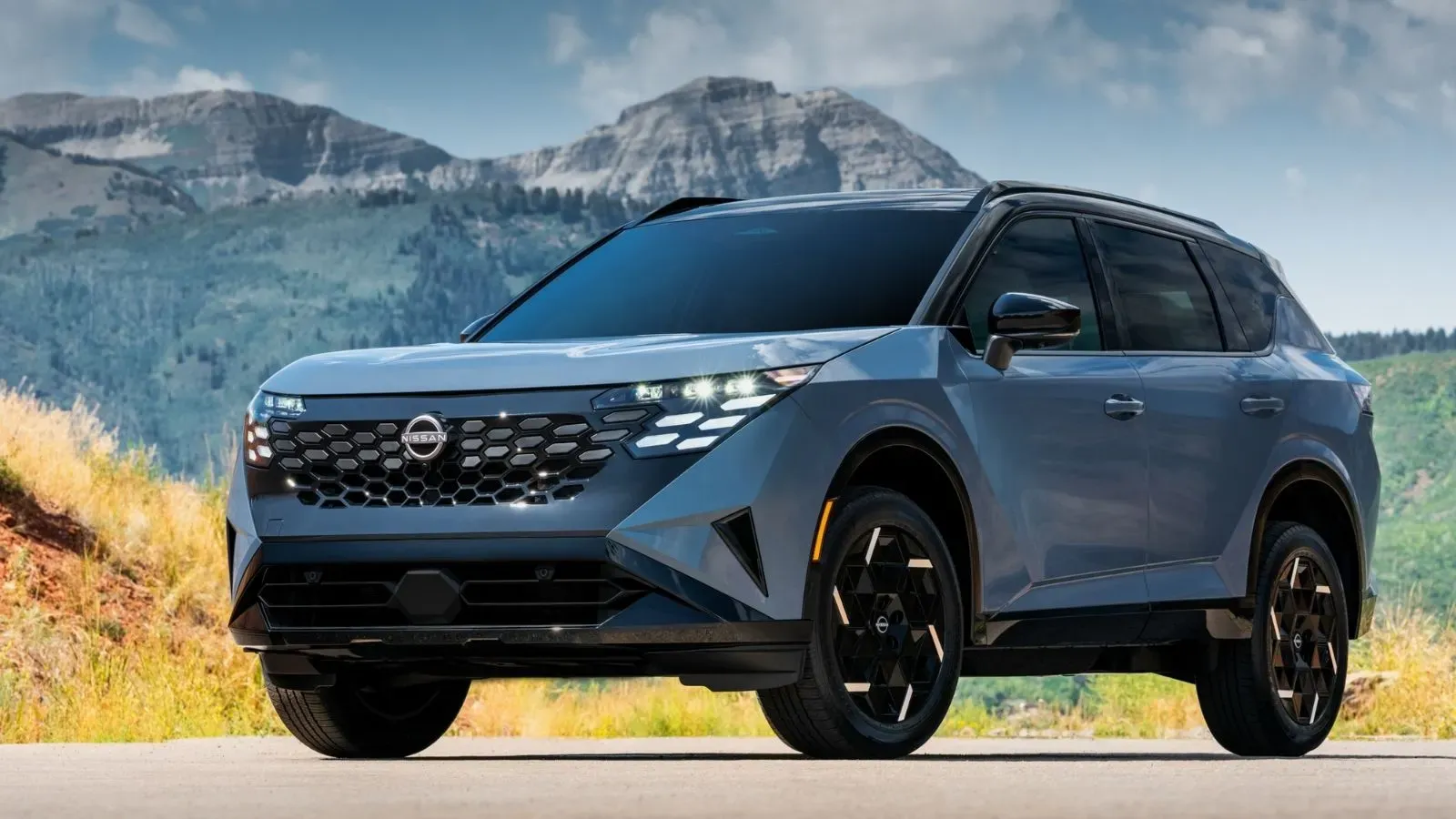 Blue 2027 Nissan Rogue Hybrid parked at an angle with a mountainous terrain in the background