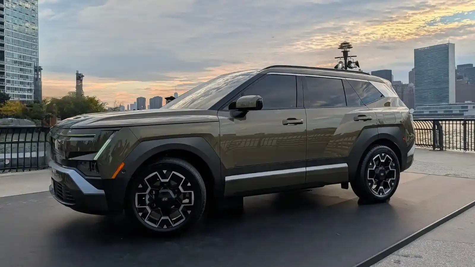 The all-new 2027 Hyundai Tucson Hybrid in a green exterior color parked with the New York City skyline in the background