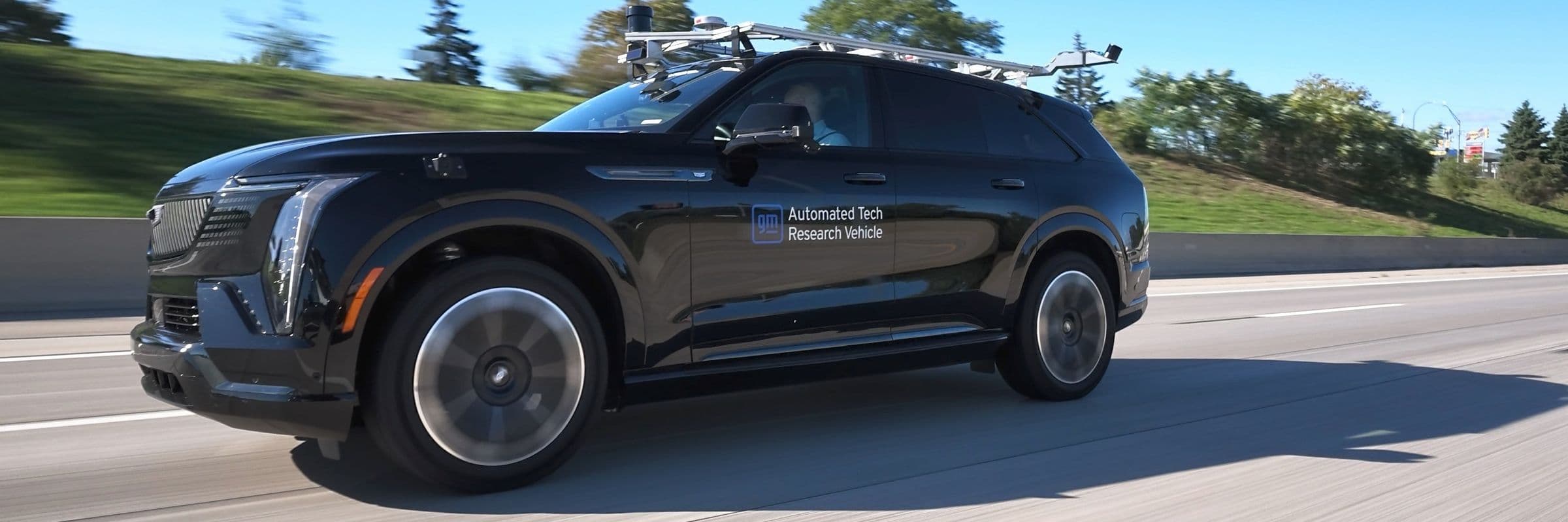 Black Cadillac Lyriq labeled as an Automated Tech Research Vehicle driving down the road