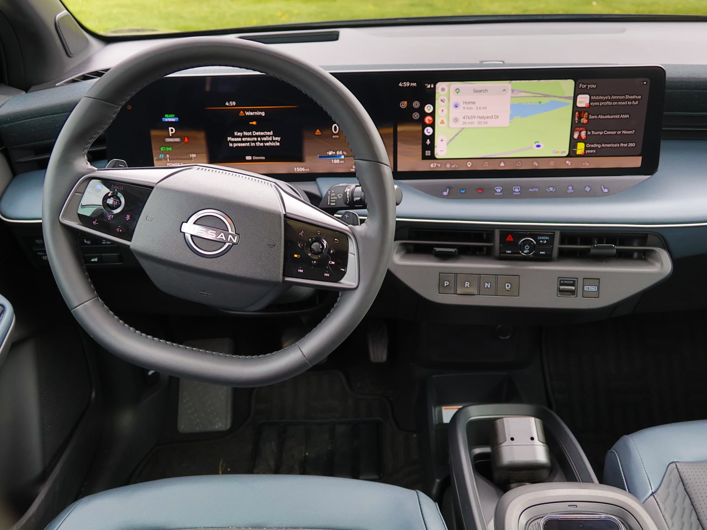 Driver's view of the Nissan Leaf dashboard with a two-spoke steering wheel, wide dual-screen display and push-button PRND gear selector.