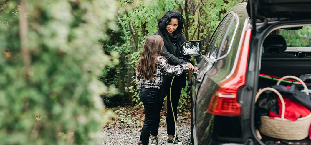 Woman and child plugging in electric car