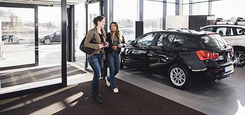 Two women walking into car dealership