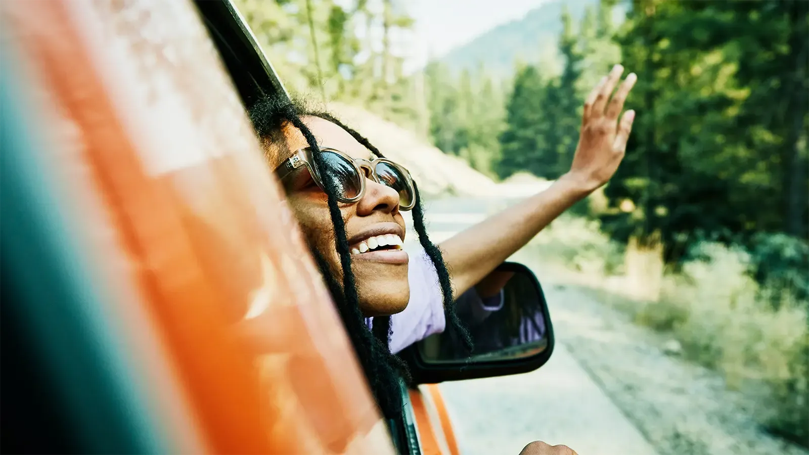 a happy person waving out the car window