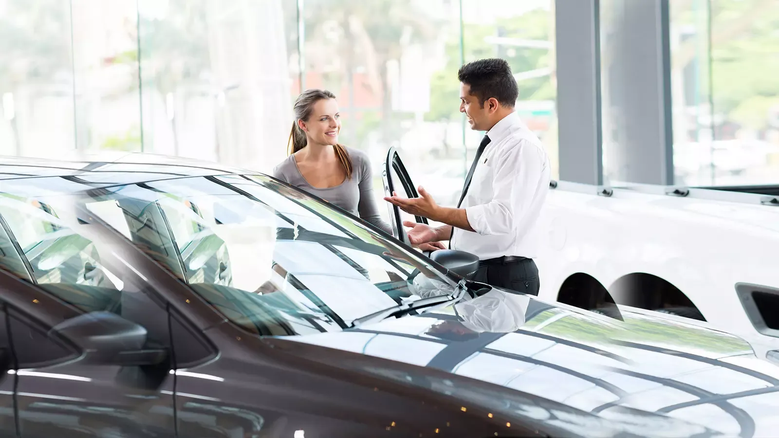 Happy sales person selling ev to woman