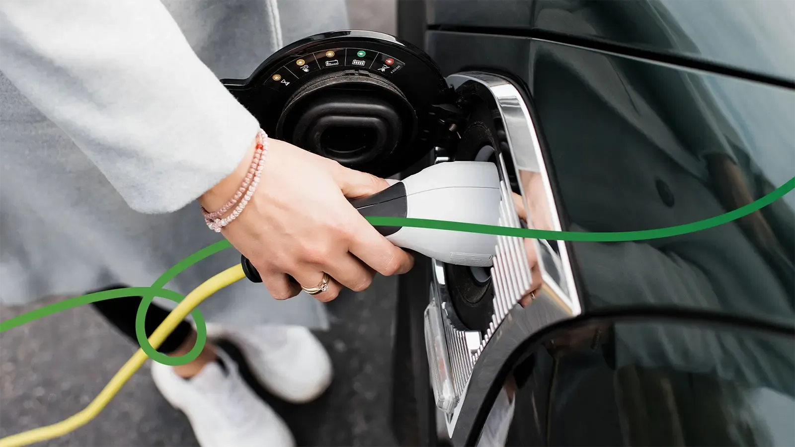 Hand plugging in EV charger with green Green Cars swirly line through hand