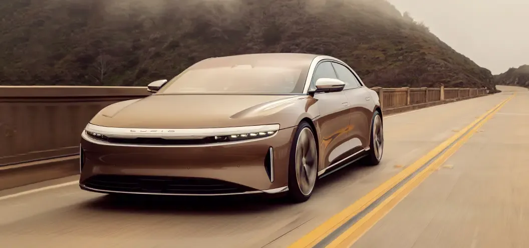 A brown Lucid Air driving across a bridge