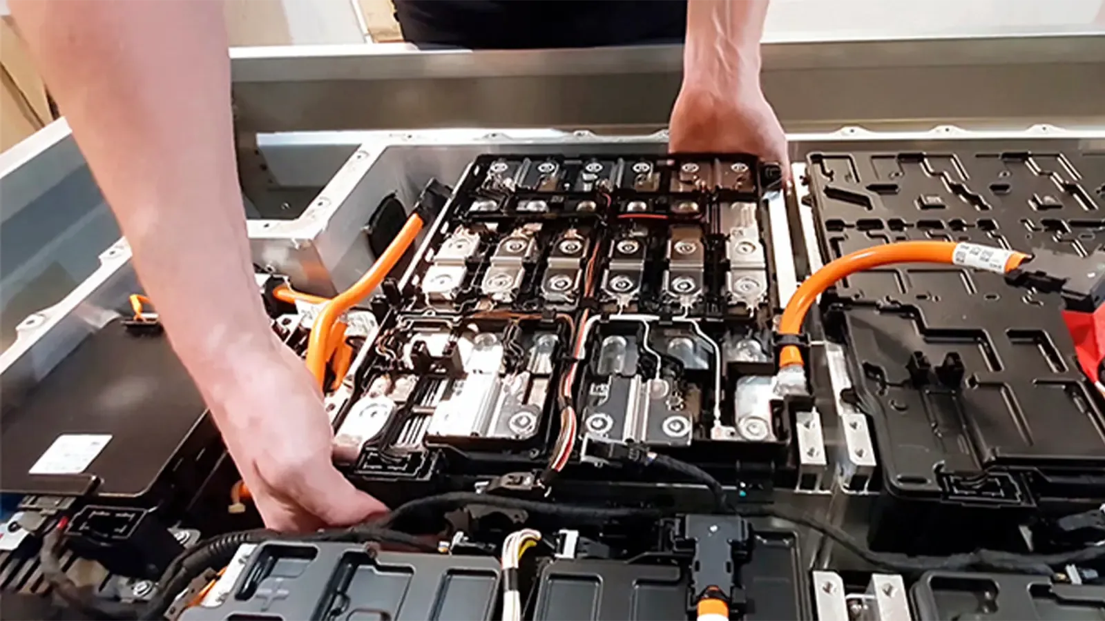 Hands reaching into a large EV battery