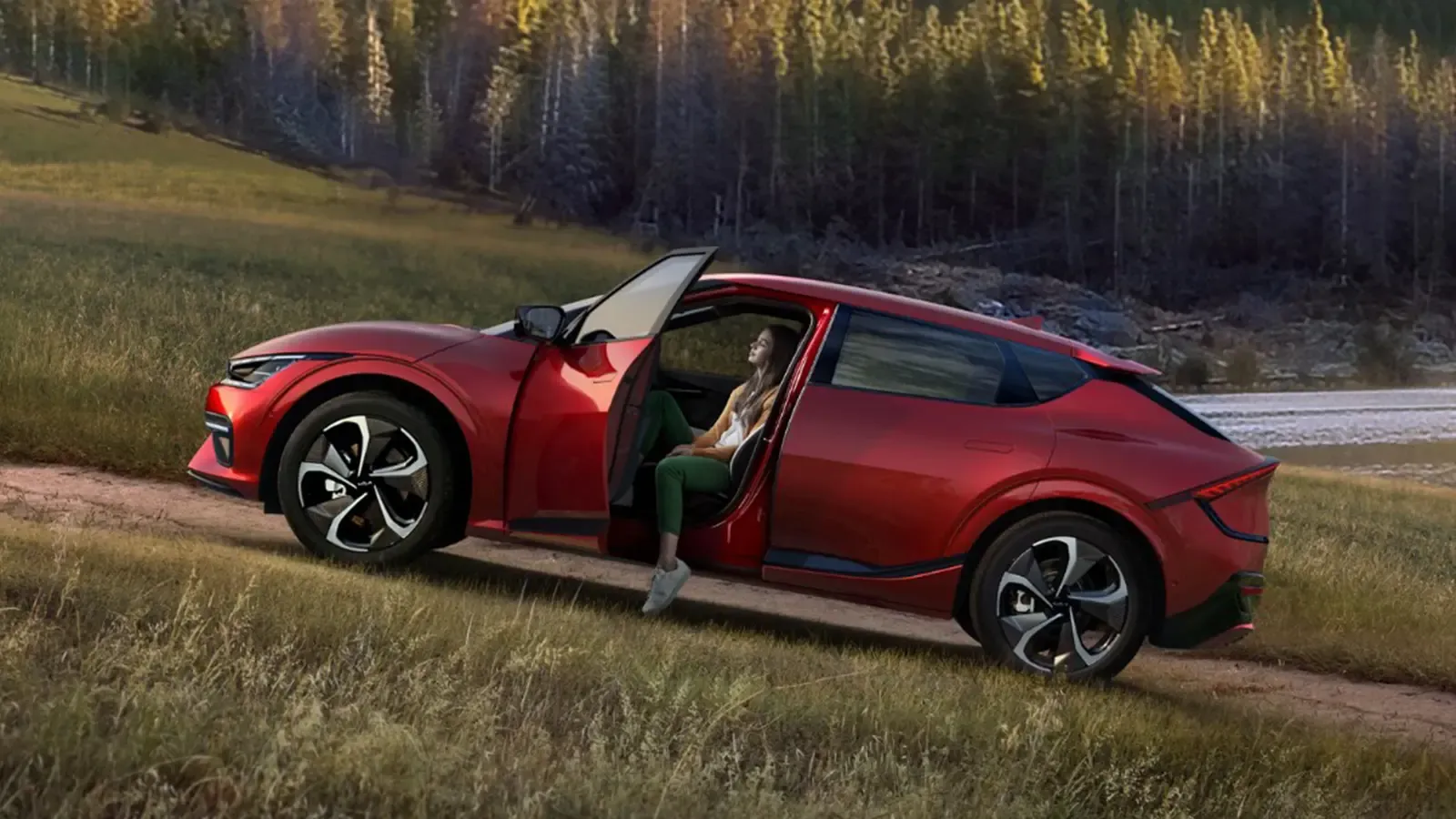 red kia EV6 parked on a grassy hill with trees in the background