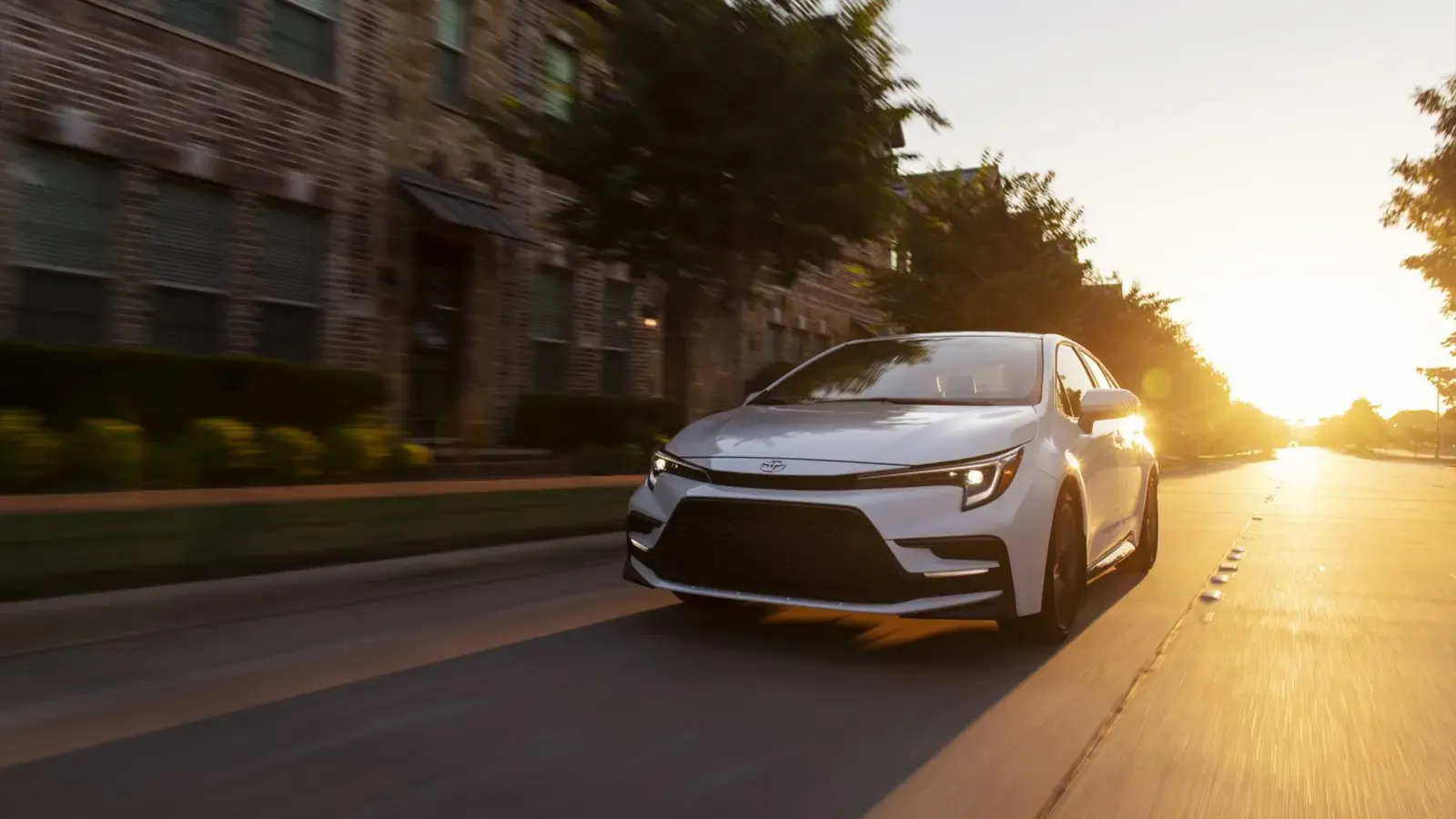 toyota corolla hybrid driving on road with setting sun in background