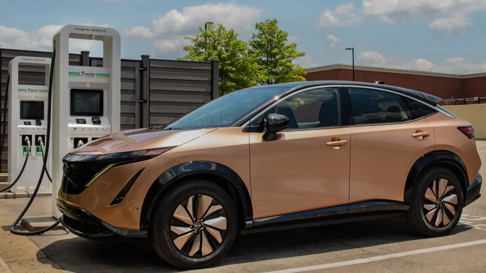 Bronze Nissan Ariya charging in a parking lot