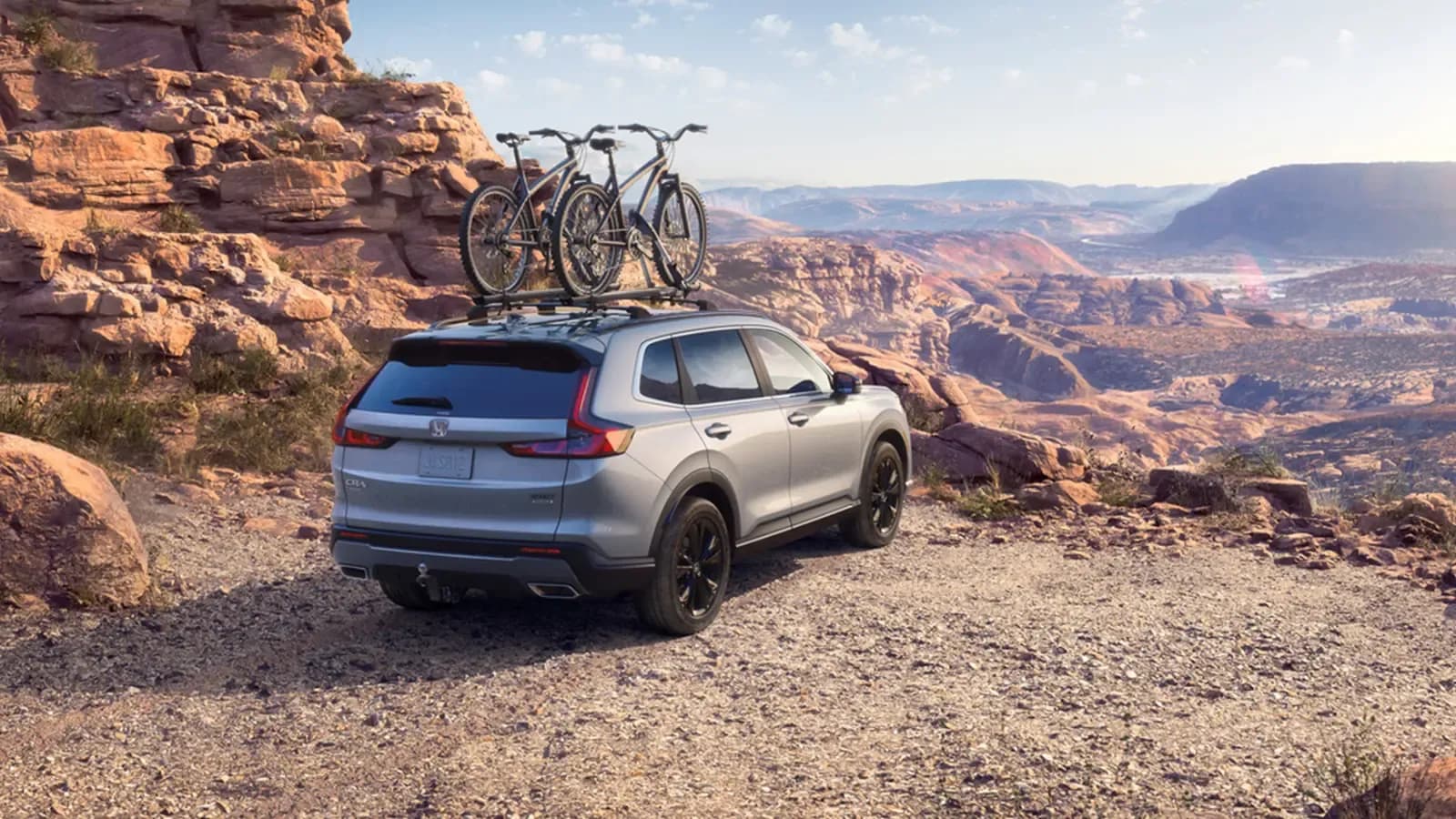 Honda CR-V parked on edge of dessert canyon with two bikes on top