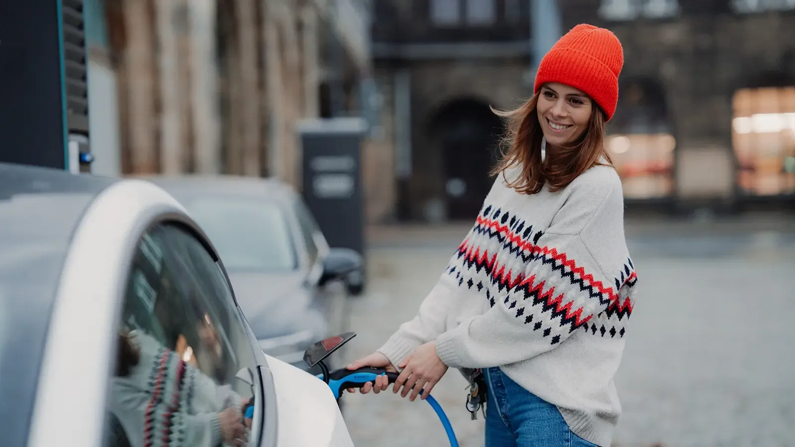 Woman pluggin in electric car in winter