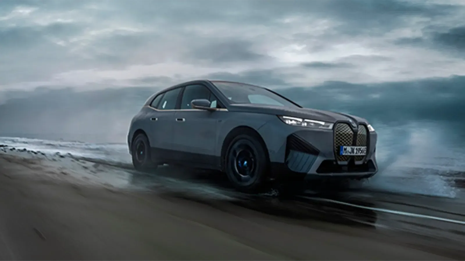 2023 BMW ix M60 driving on the beach side front profile