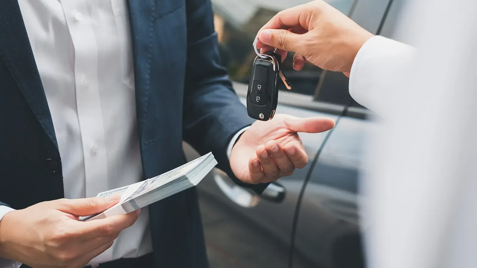 Closeup hand giving a car key and money for car lease