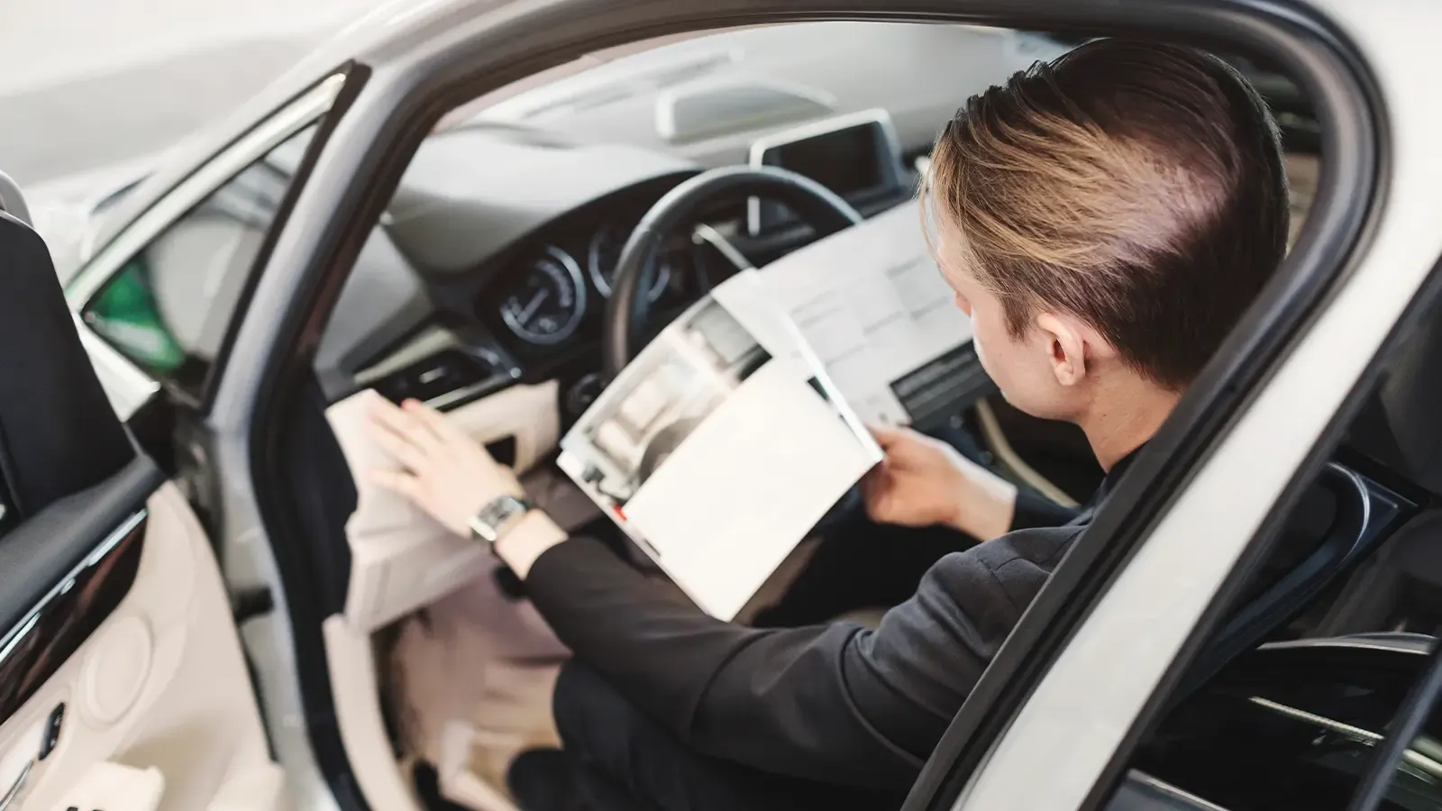 Person Sitting Inside A Car Reading A Manual