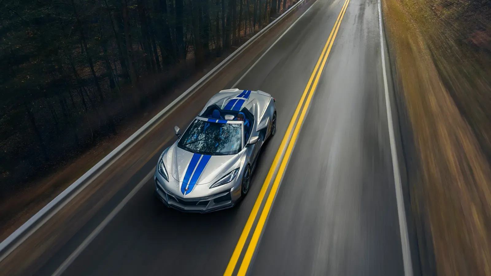Corvette driving fast down wooded highway