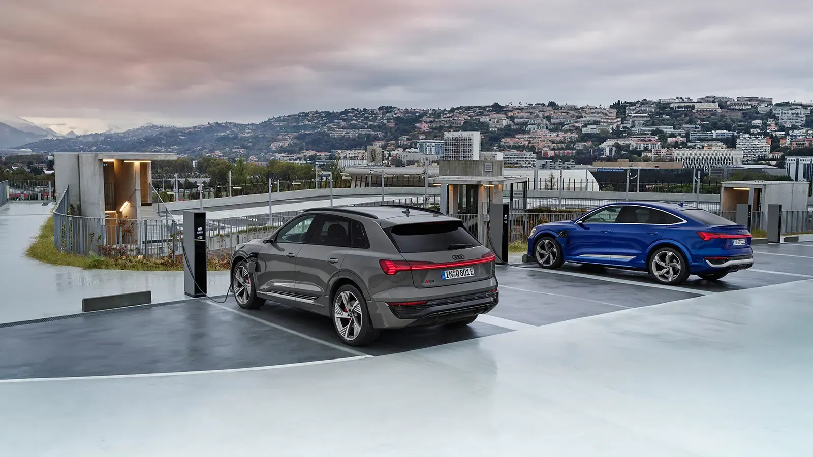 Two Audi's charging with a city view