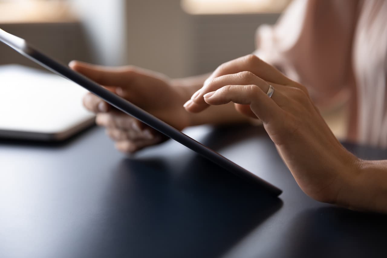 Hands holding and scrolling on a tablet.