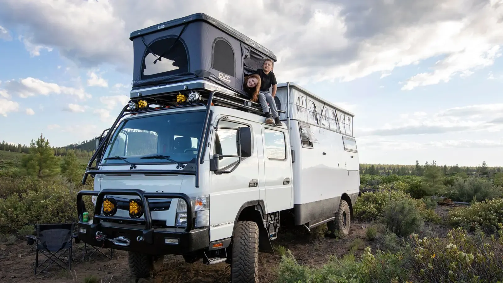 Children sitting on top of Dual EXP EarthCruiser RV outdoors.