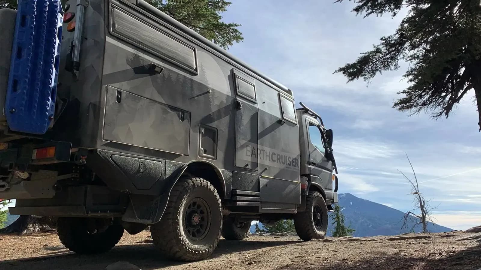 Side exterior of EarthCruiser driving by mountains and plains.