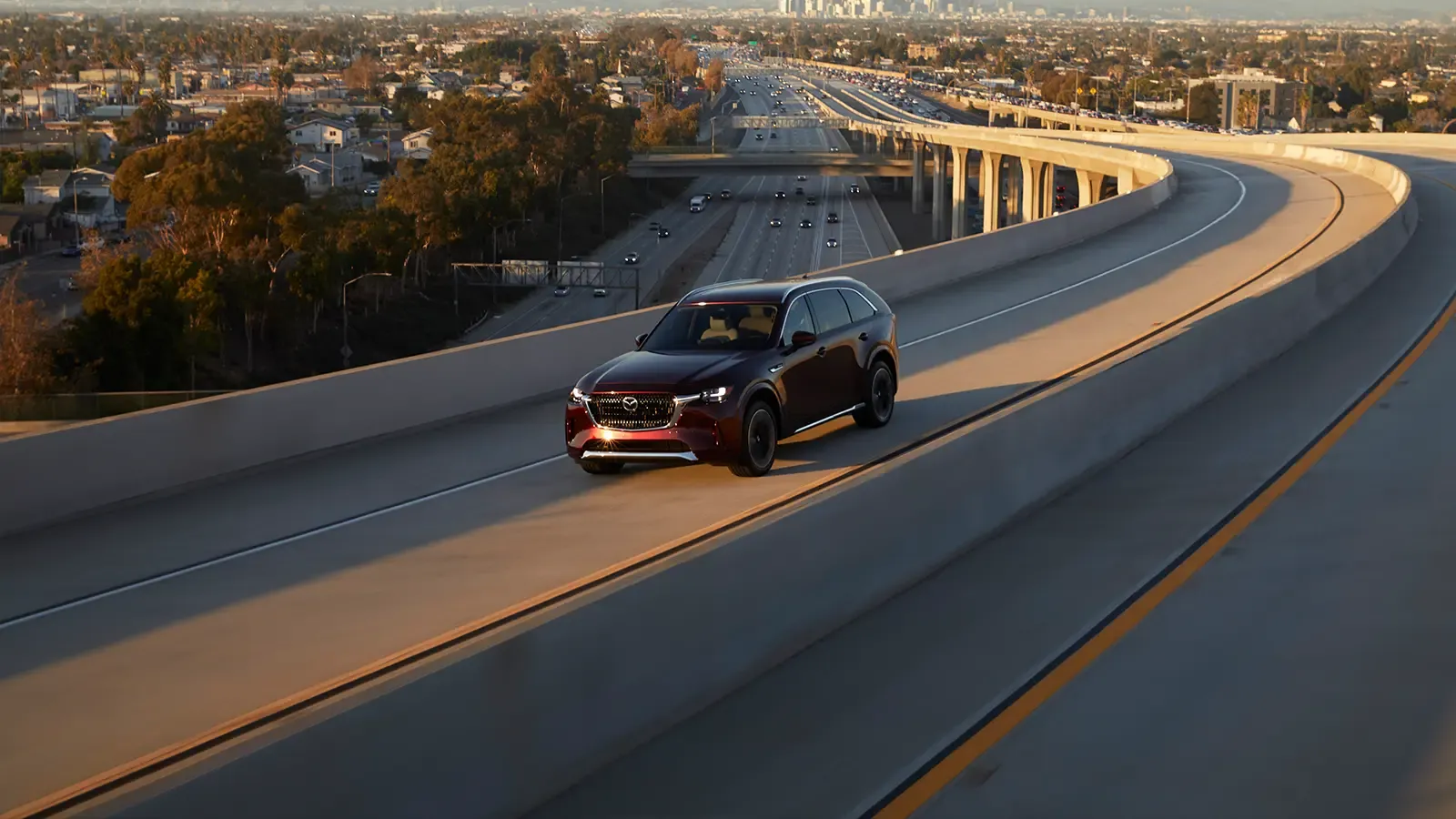 Burgundy Mazda CX-90 driving on the highway.