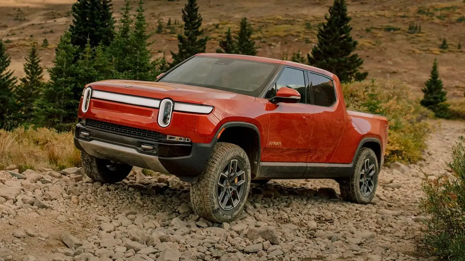 Rivian R1T Red pickup truck going up hill