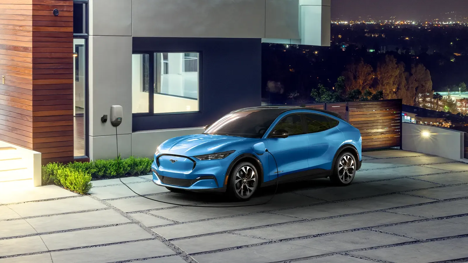 Ford Mach-E parked and charging outside a house overlooking city lights