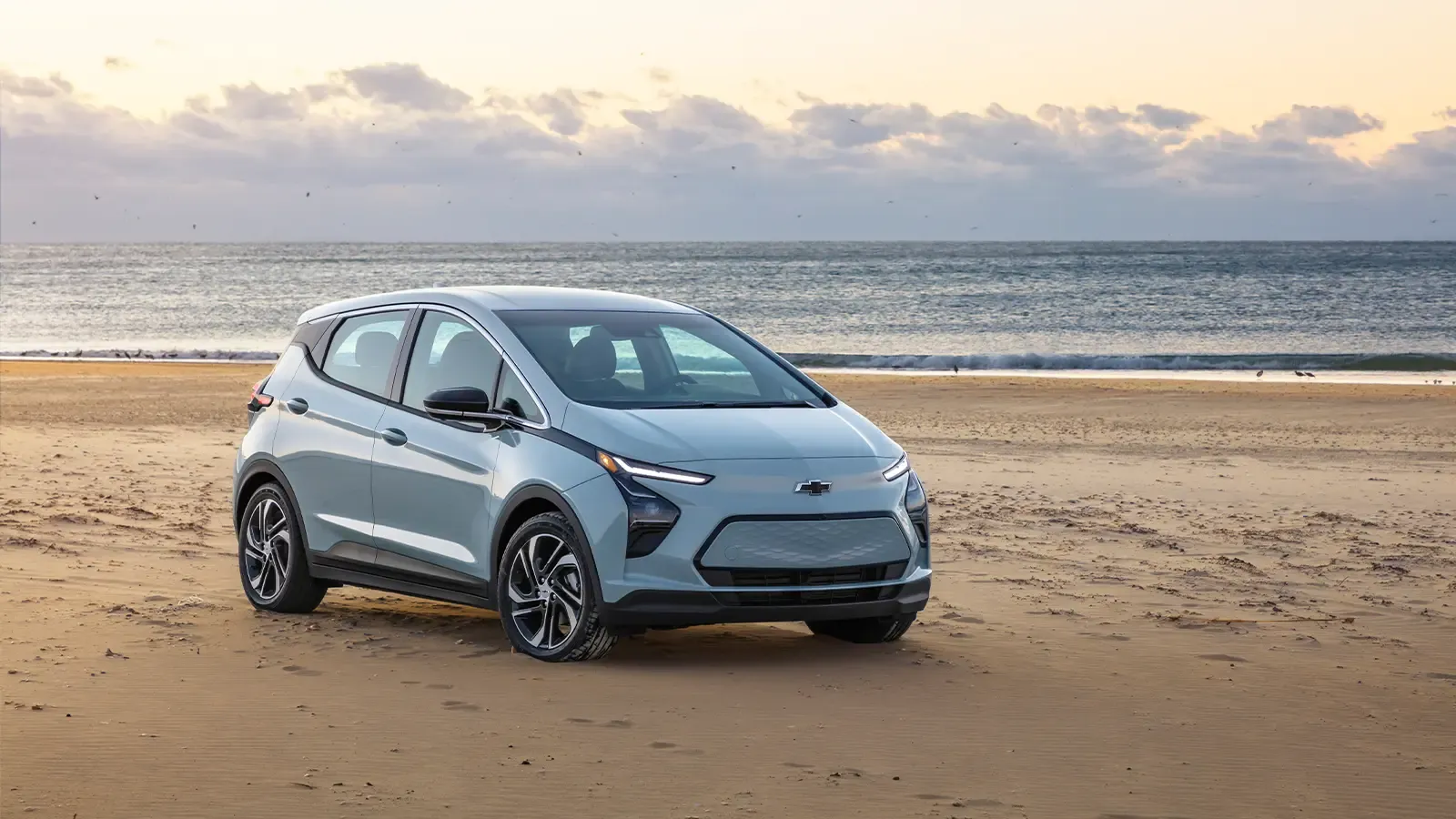 Chevy Bolt EV parked on a sandy beach during sunset