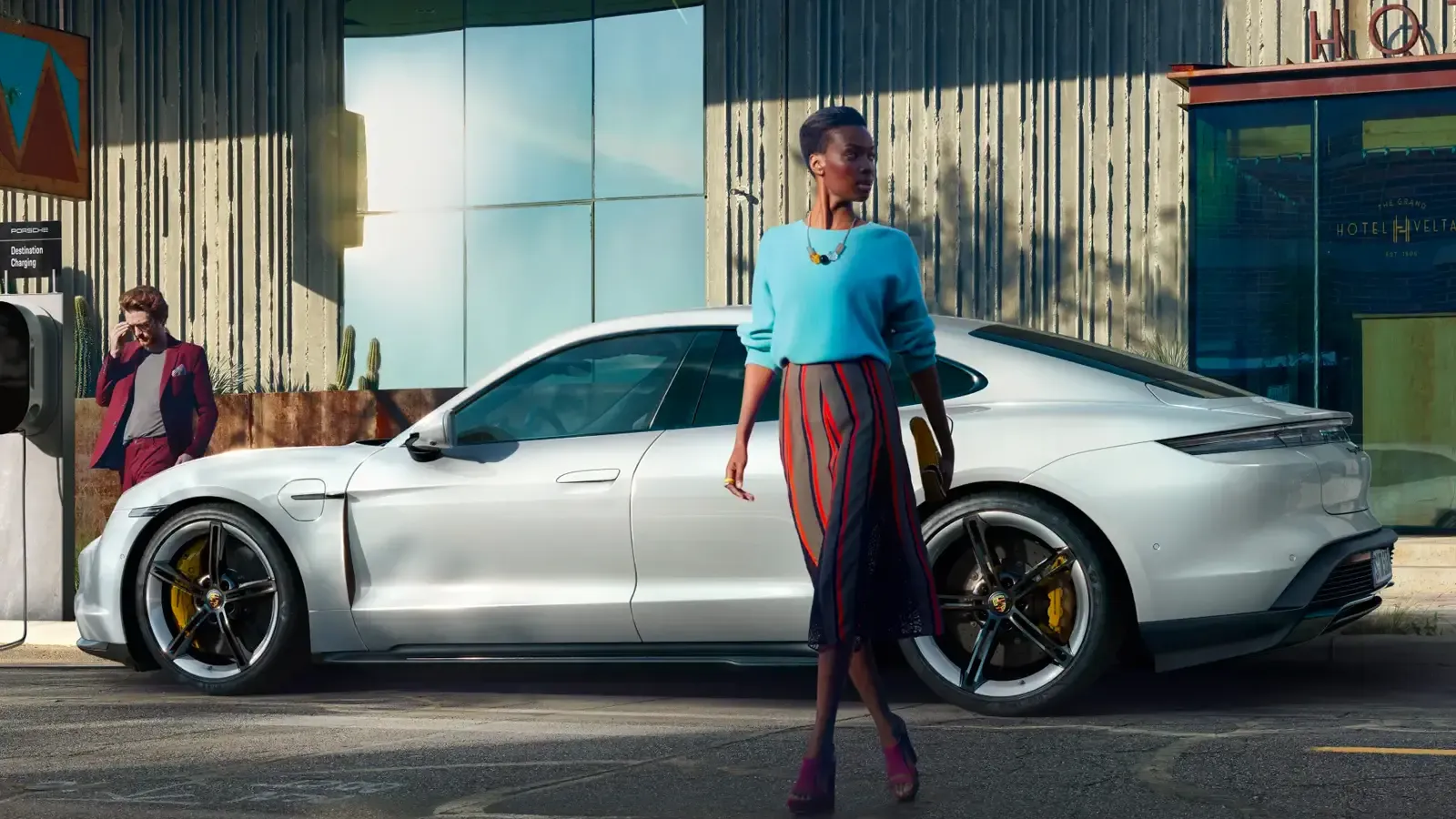 Woman passing by a white Porsche Taycan 4S parked by a hotel