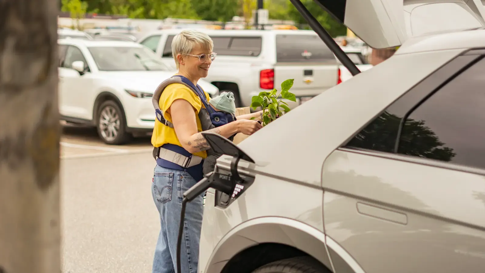 Car charging as a parent puts away groceries into the trunk