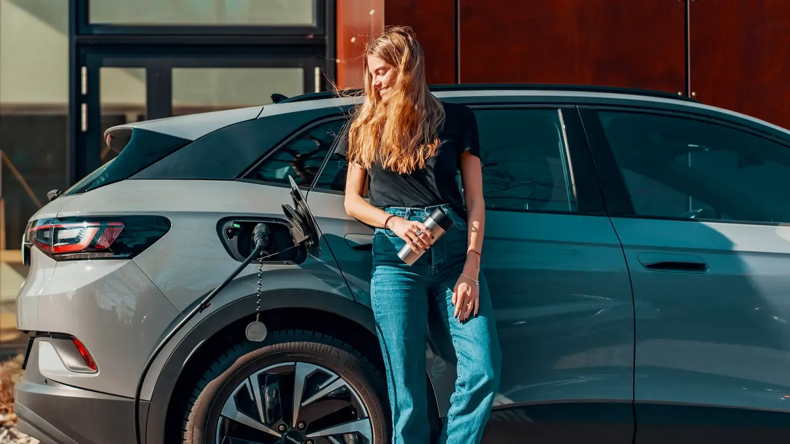 Woman standing and happily glancing at her car charging