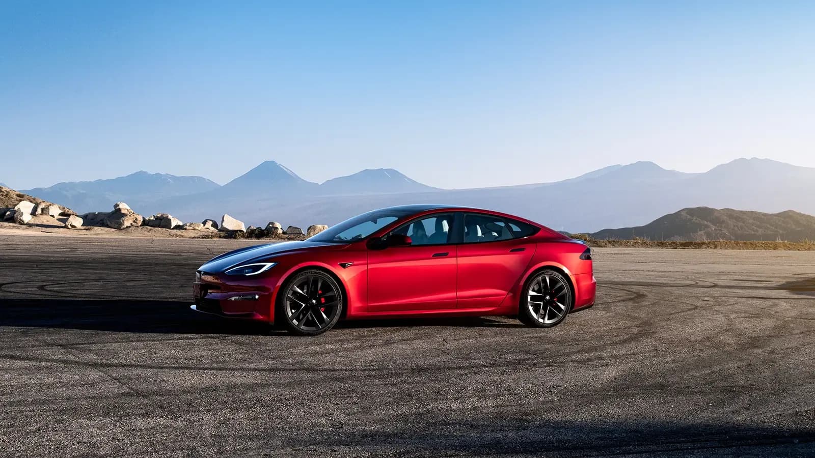 Tesla Model S parked by mountain scenery.