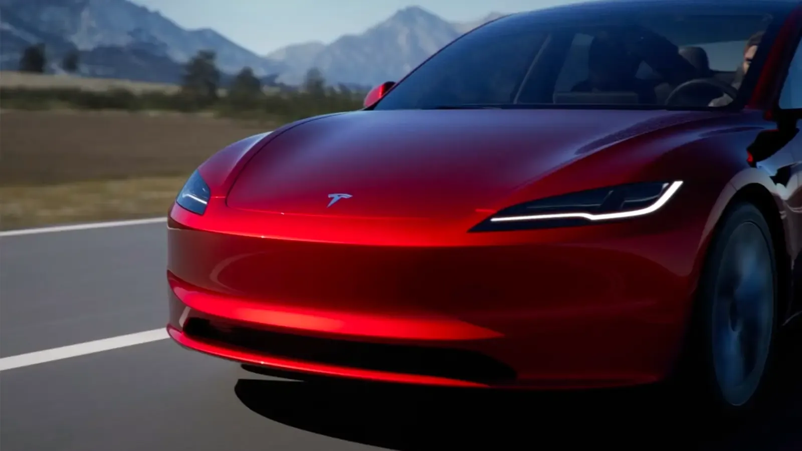 close up of a red Tesla Model 3 driving on the road
