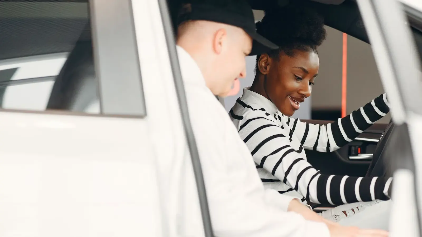People happily sitting inside a car in a dealership