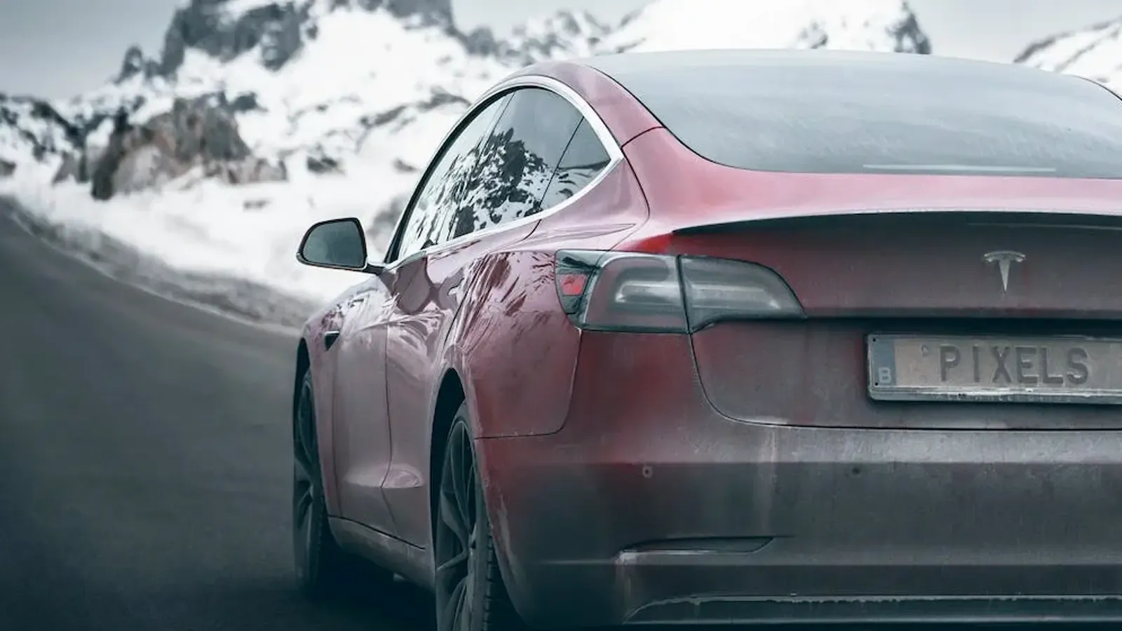 a frosted Tesla driving on a wintery road