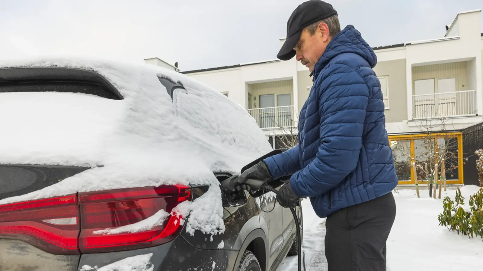 Man charging his car in snowy conditions