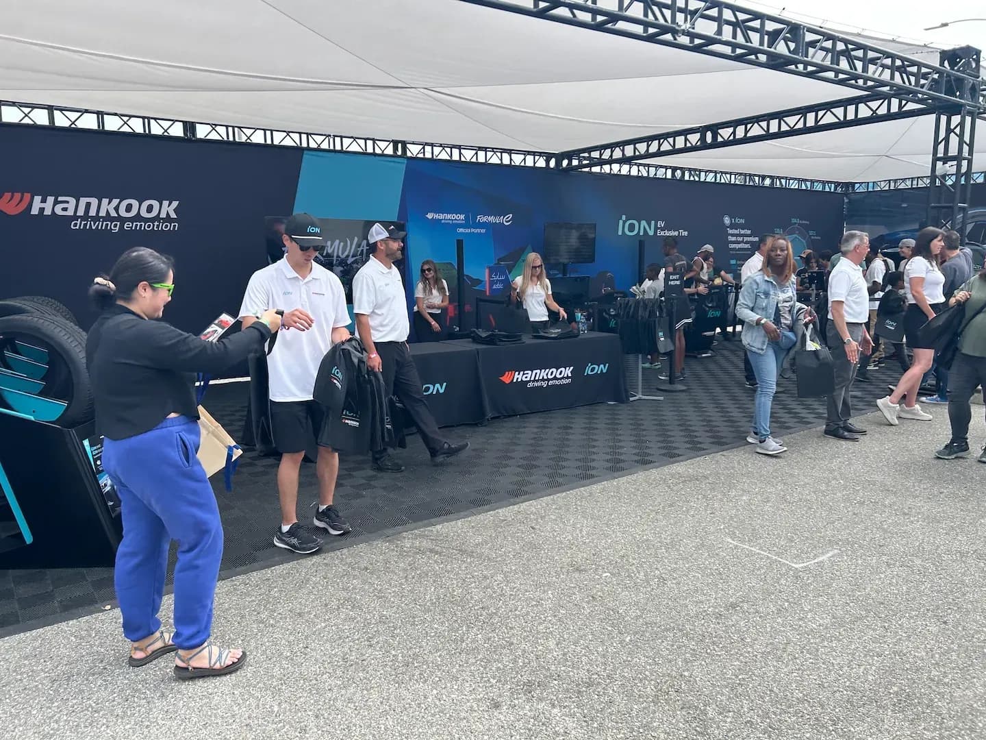 Varias personas están en un puesto de Hankook iON bajo una carpa en Electrify Expo.