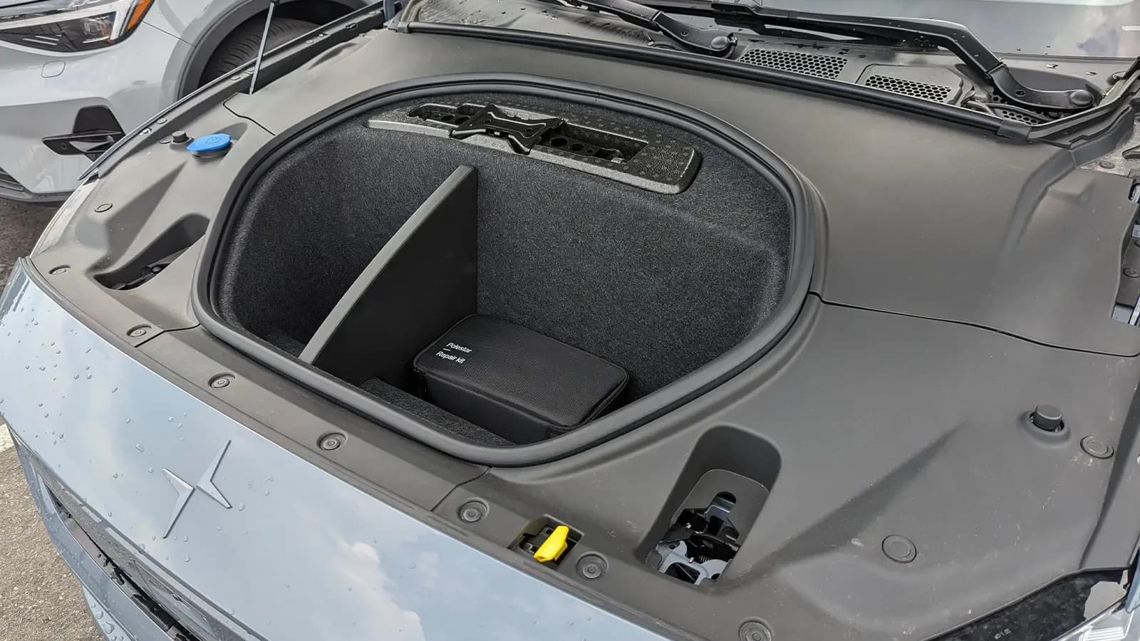 Open Polestar 2 front trunk with a storage well and repair kit.