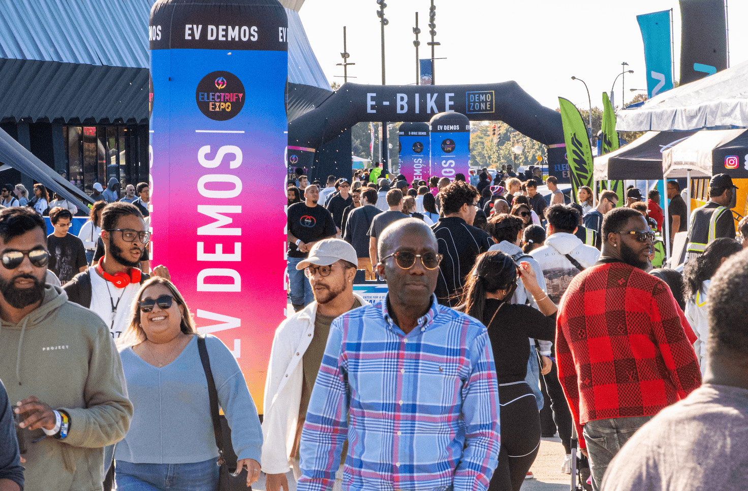 Una multitud camina junto a demostraciones de EV y una zona de demostración de E-BIKE en Electrify Expo.