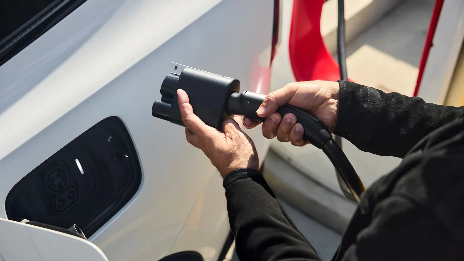 person charging EV at Tesla Supercharger