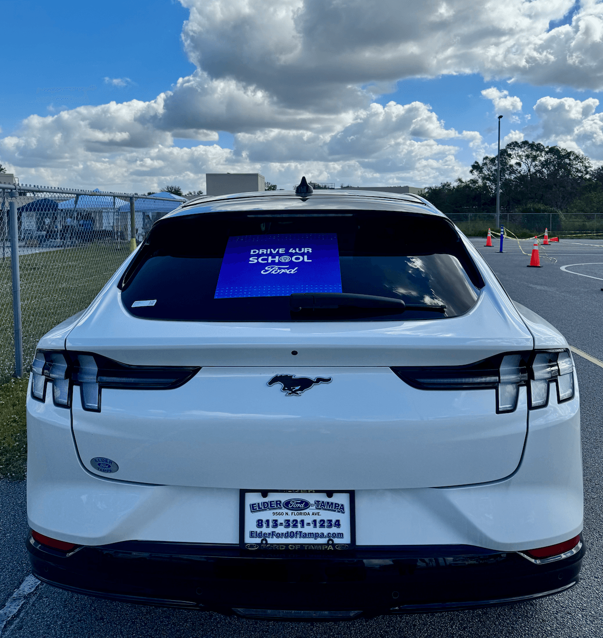 Rear view of a white Ford SUV with a Drive 4 UR School sign in the back window.
