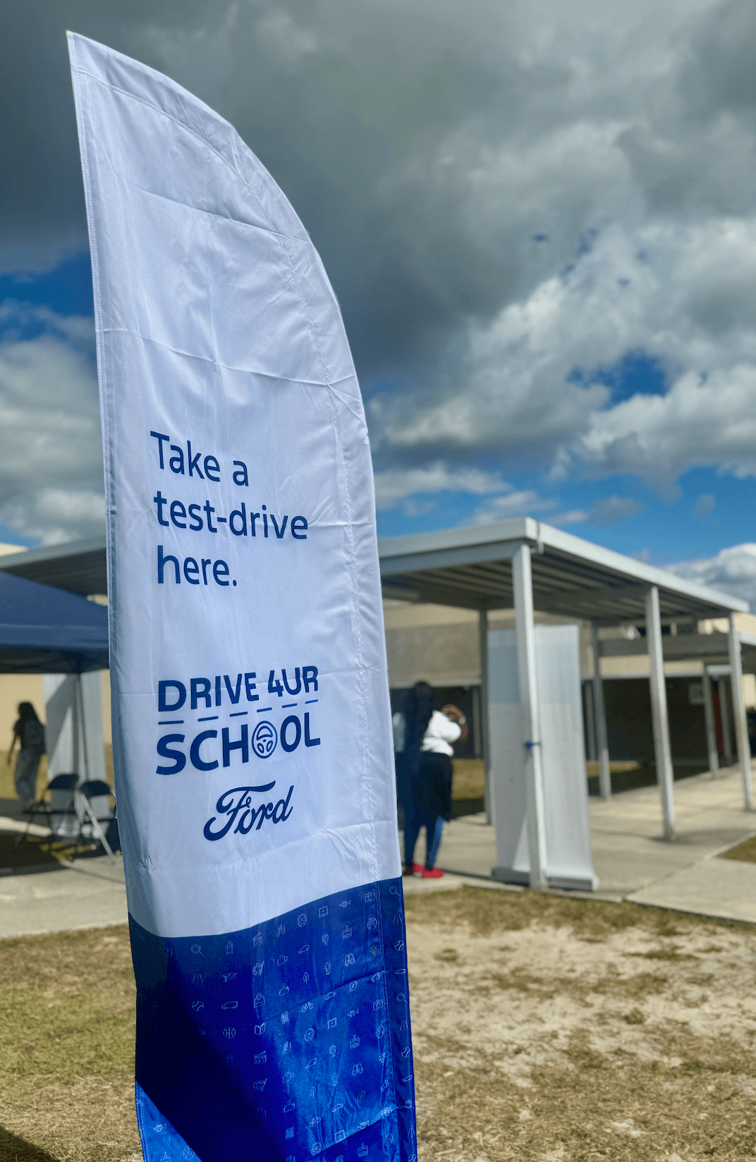 A Ford Drive 4 UR School banner stands outdoors beside a covered walkway.