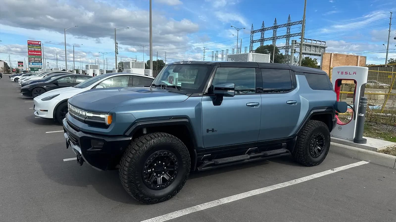 blue GMC Hummer EV using Tesla charger