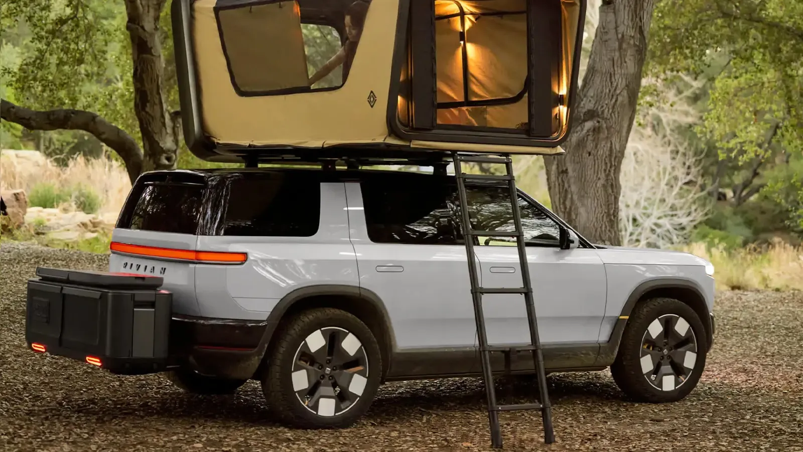 Rivian parked under a tree with camping tent