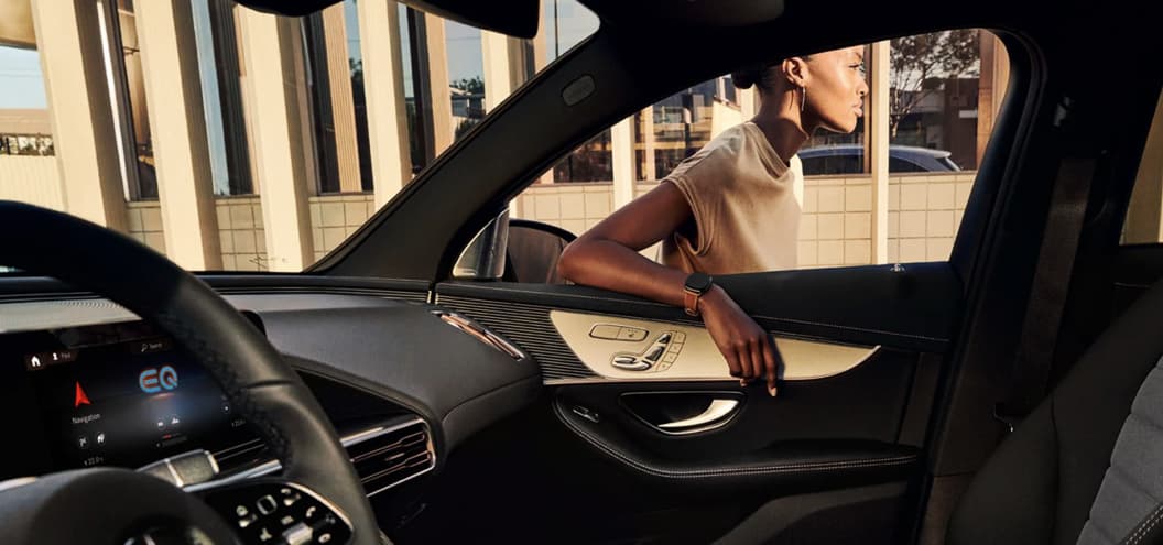 Woman standing outside a Mercedes Benz EQA