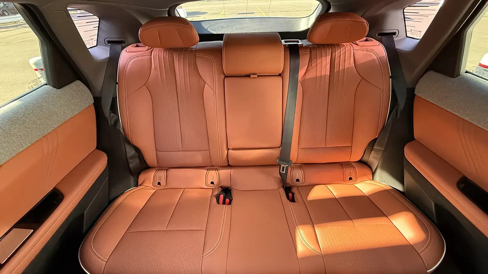 Rear seat of a Cadillac Optiq with three tan seats and headrests.