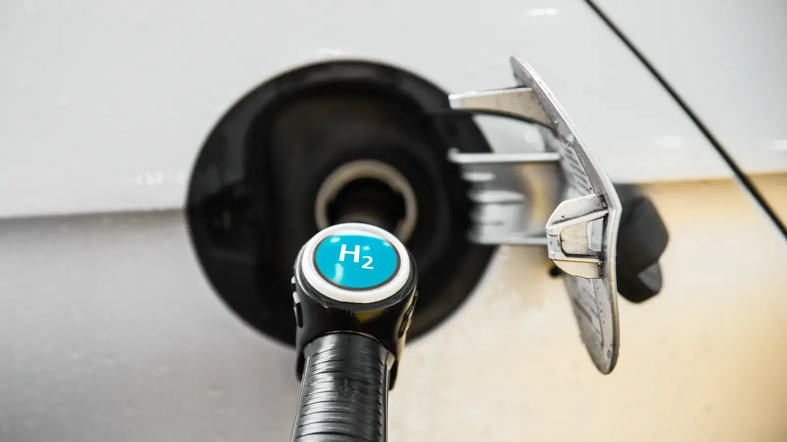a hydrogen car being charged with the symbol "H2" on the charging cable