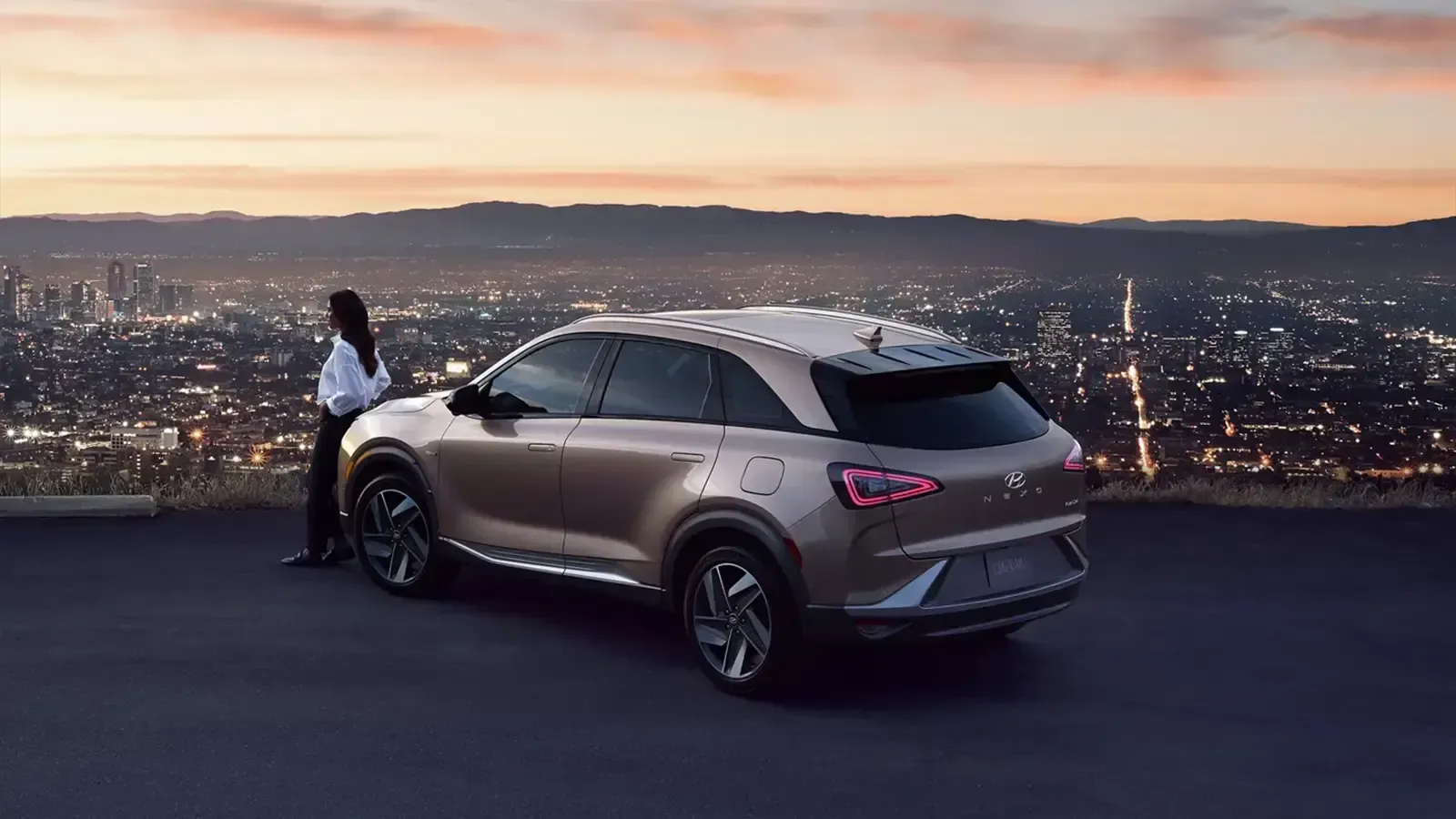 image of a woman leaning against the Hyundai Nexo overlooking a city