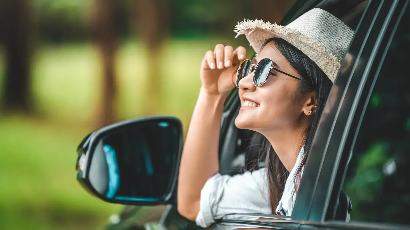 Lady wearing sunglasses and weaved had looking out of car window